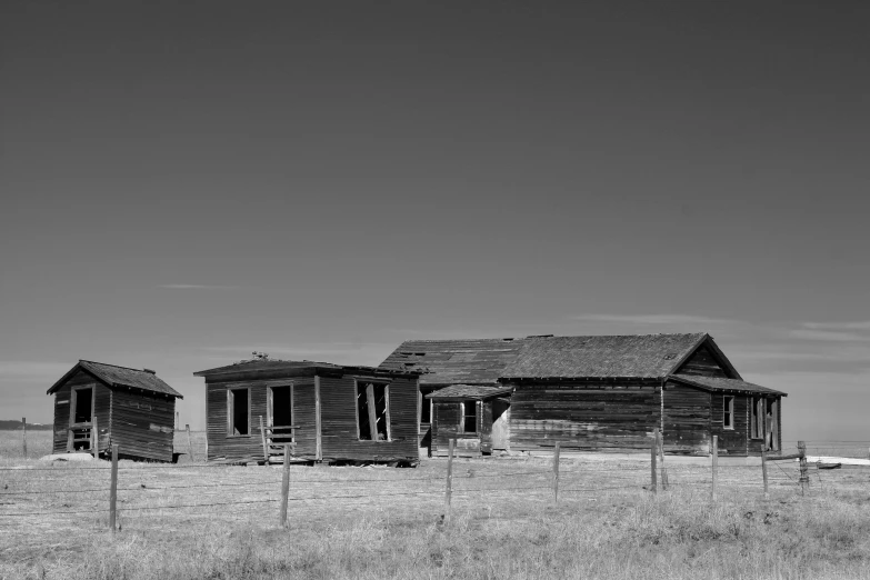 three old weathered wooden cabins in a fenced in area