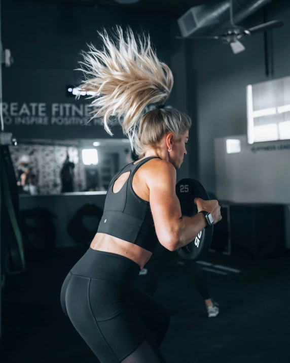 a woman standing in a gym with her hair flying around