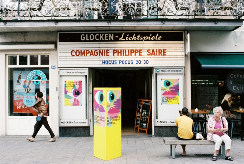 there are people sitting on benches outside of a shop