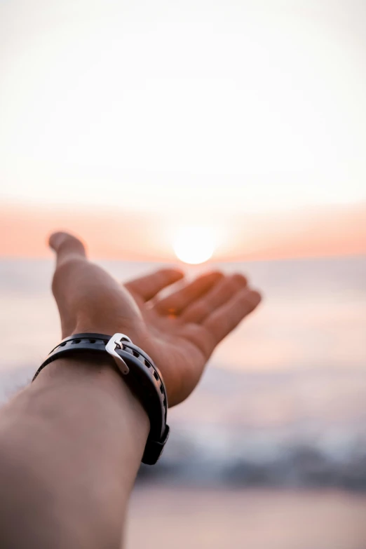 a woman is holding her arm out with the sun setting in the background