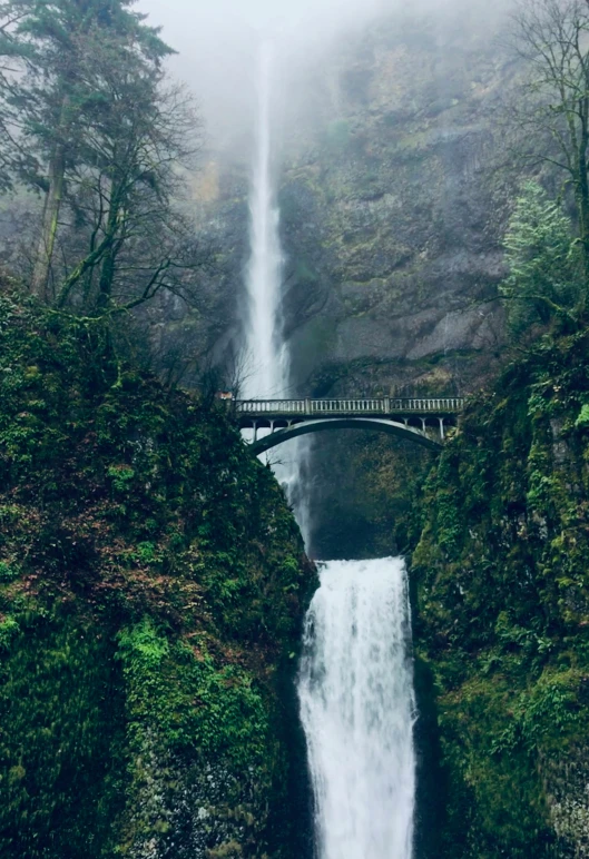 a bridge crossing over water with a waterfall near by