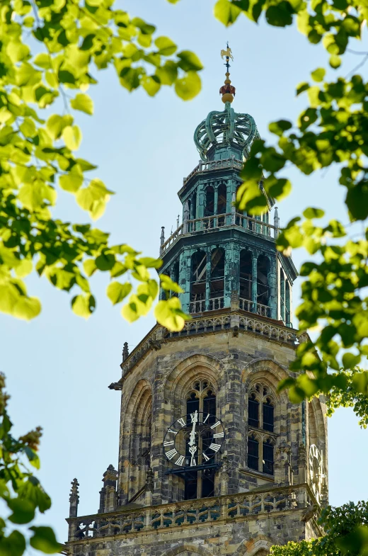 a green clock tower stands tall and has a sky background