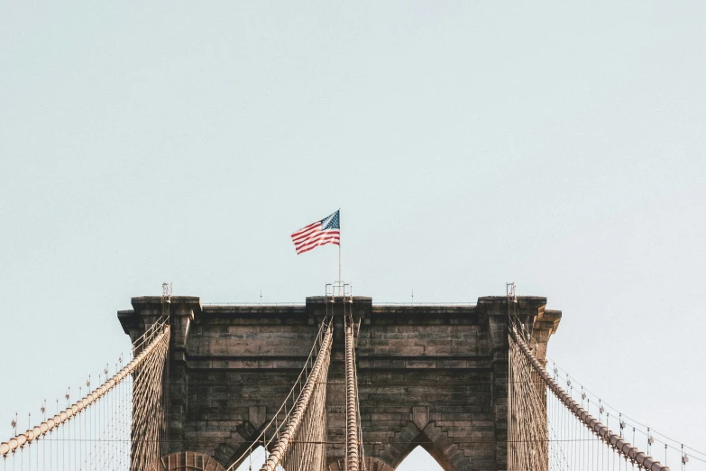 an american flag flying above the bridge during a sunny day
