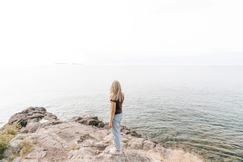 a girl standing on a cliff overlooking the ocean