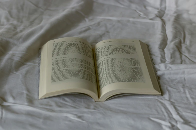 a book is laying on the bed, with the pages folded up