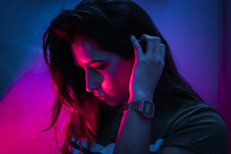a woman wearing a celet around her wrist with purple light behind