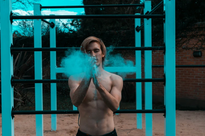 a man in trunks is throwing blue powder on his face