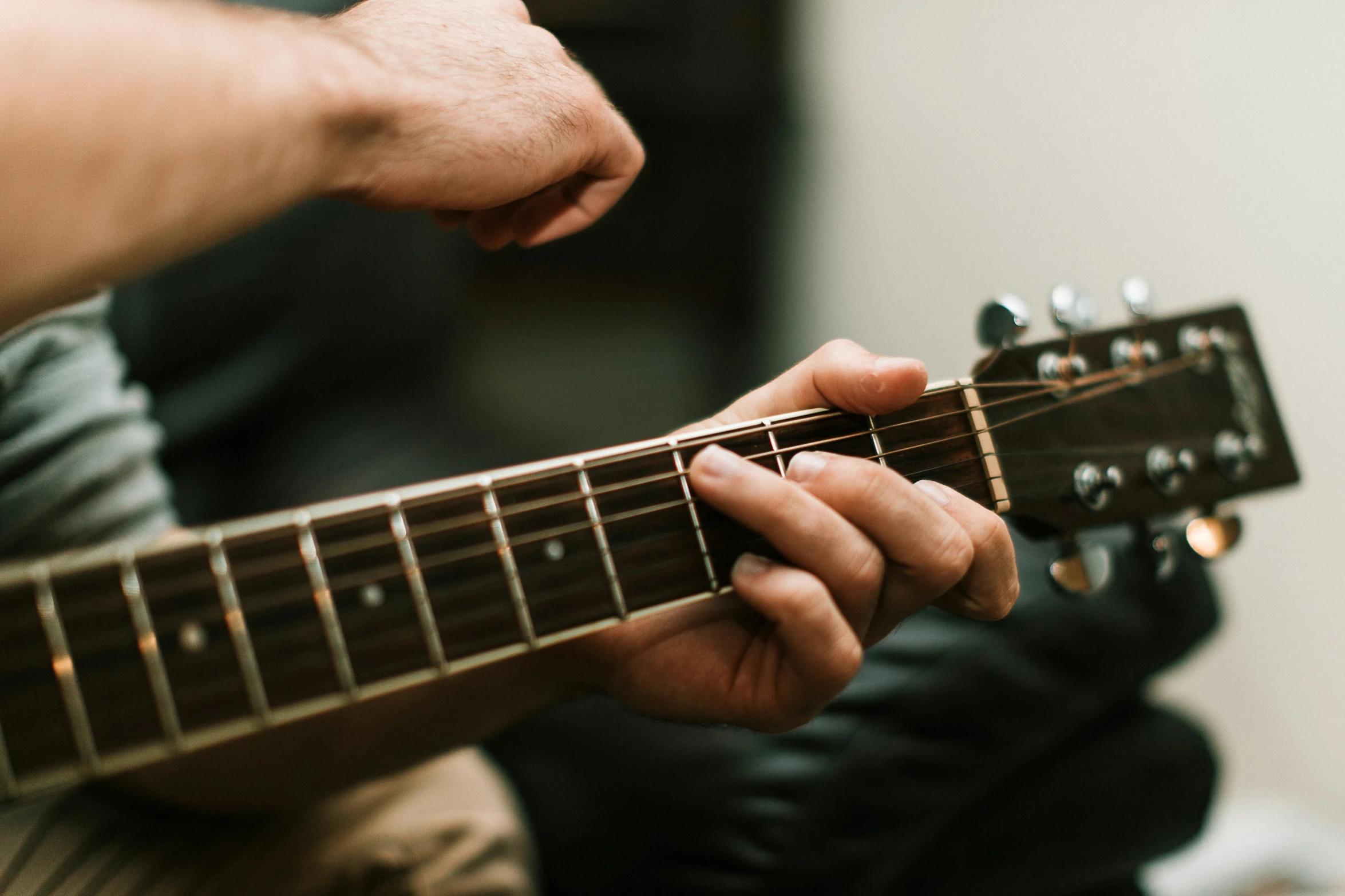 a man is playing an acoustic guitar while sitting on his lap