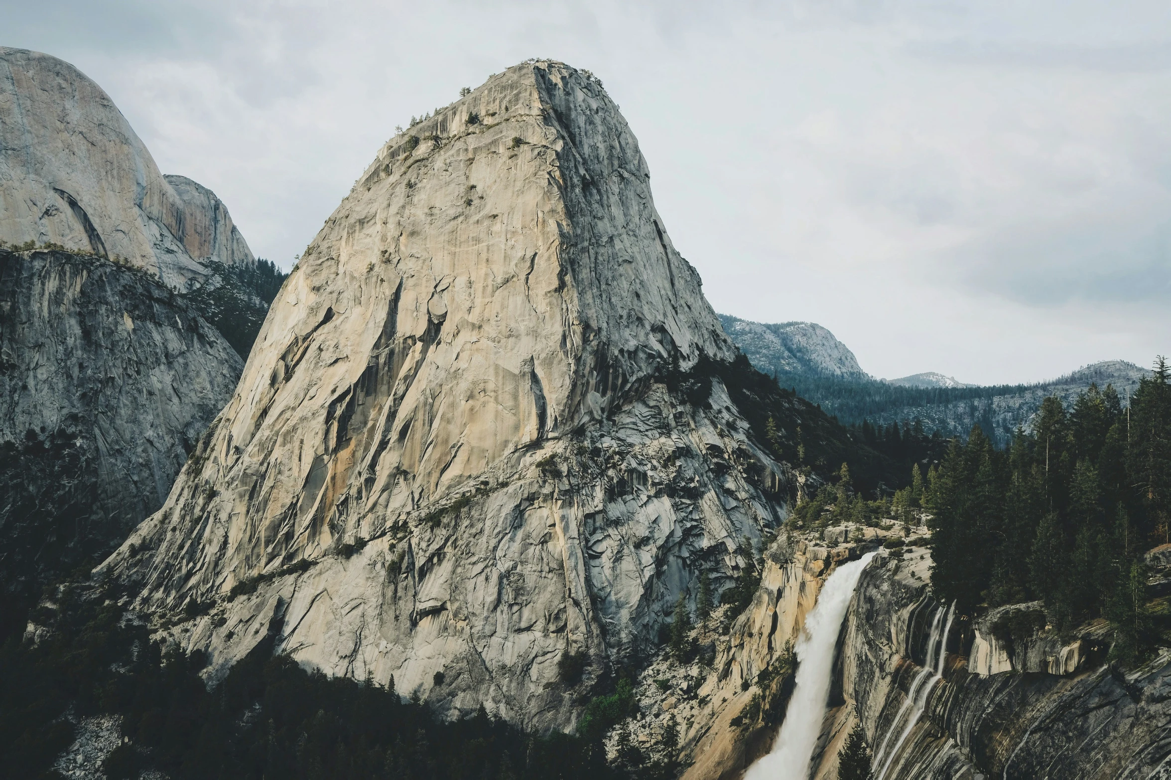 the water fall is at the base of the rocky mountain