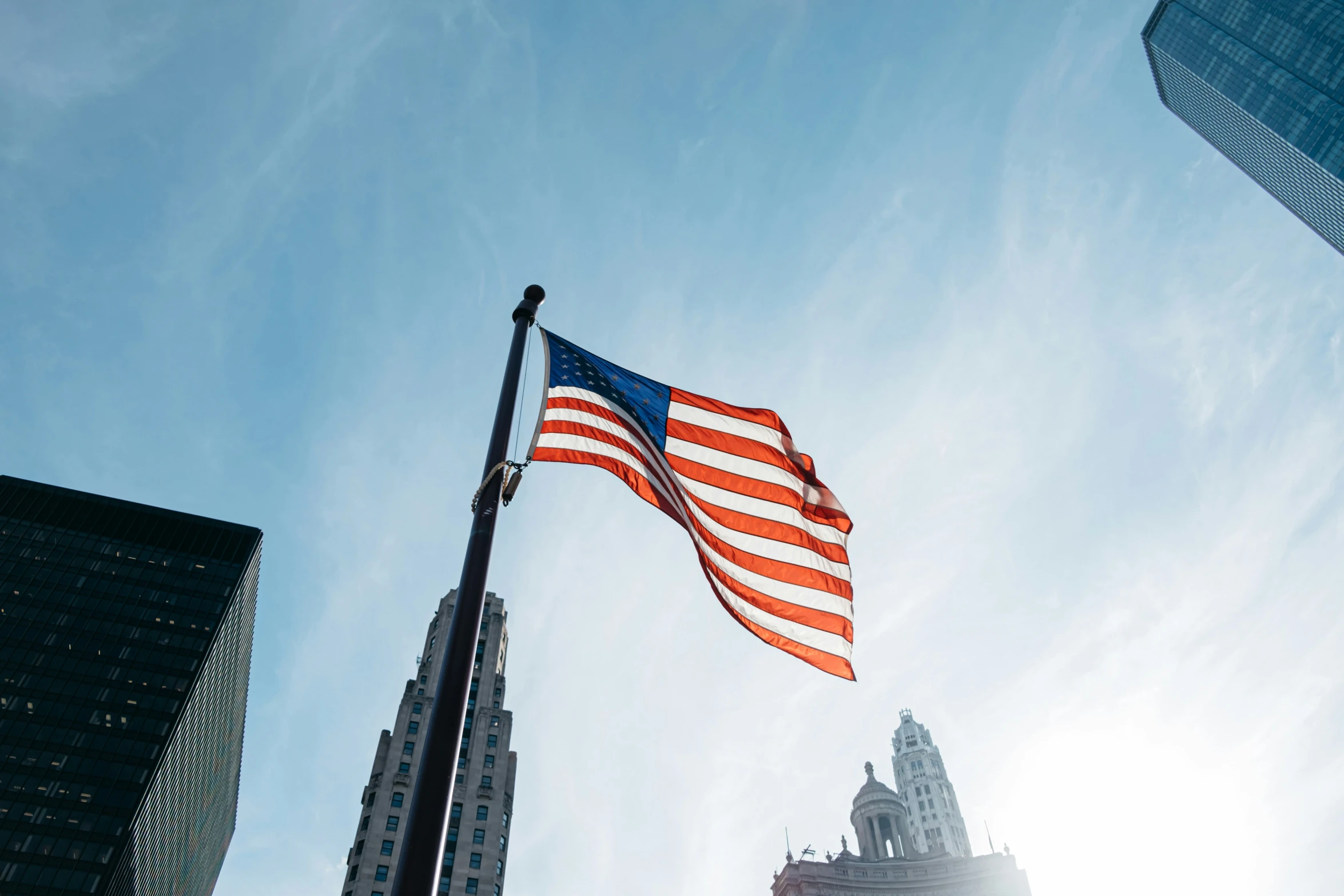 an american flag flying high above skyscrs