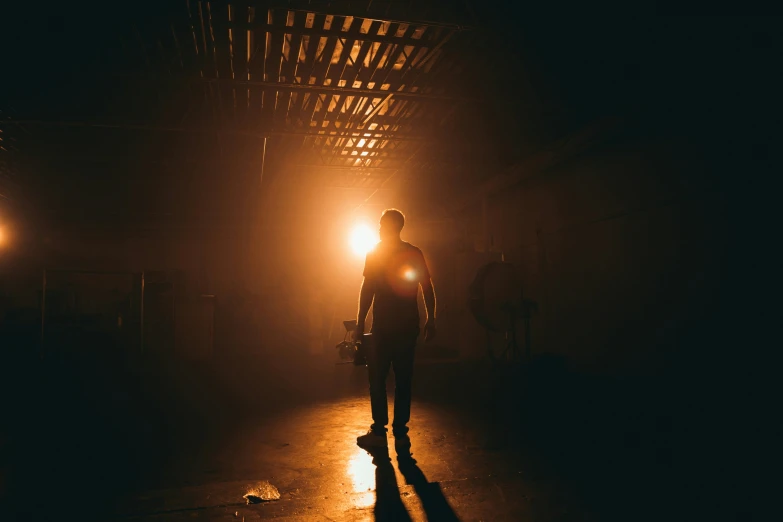 a man stands under a lit up street light in the dark