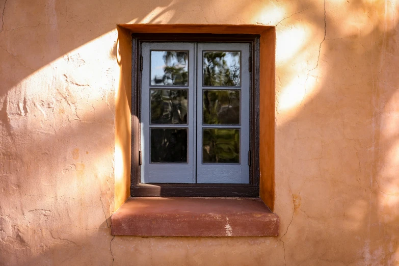 a window with a frame and brown trim sitting against a wall