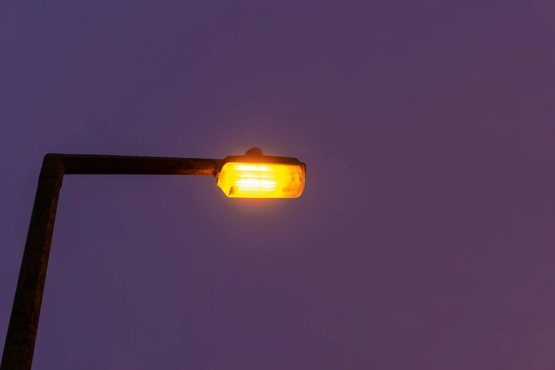 a street light that is on and some sky