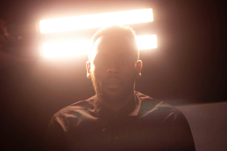 man with earbuds standing at light in dark room