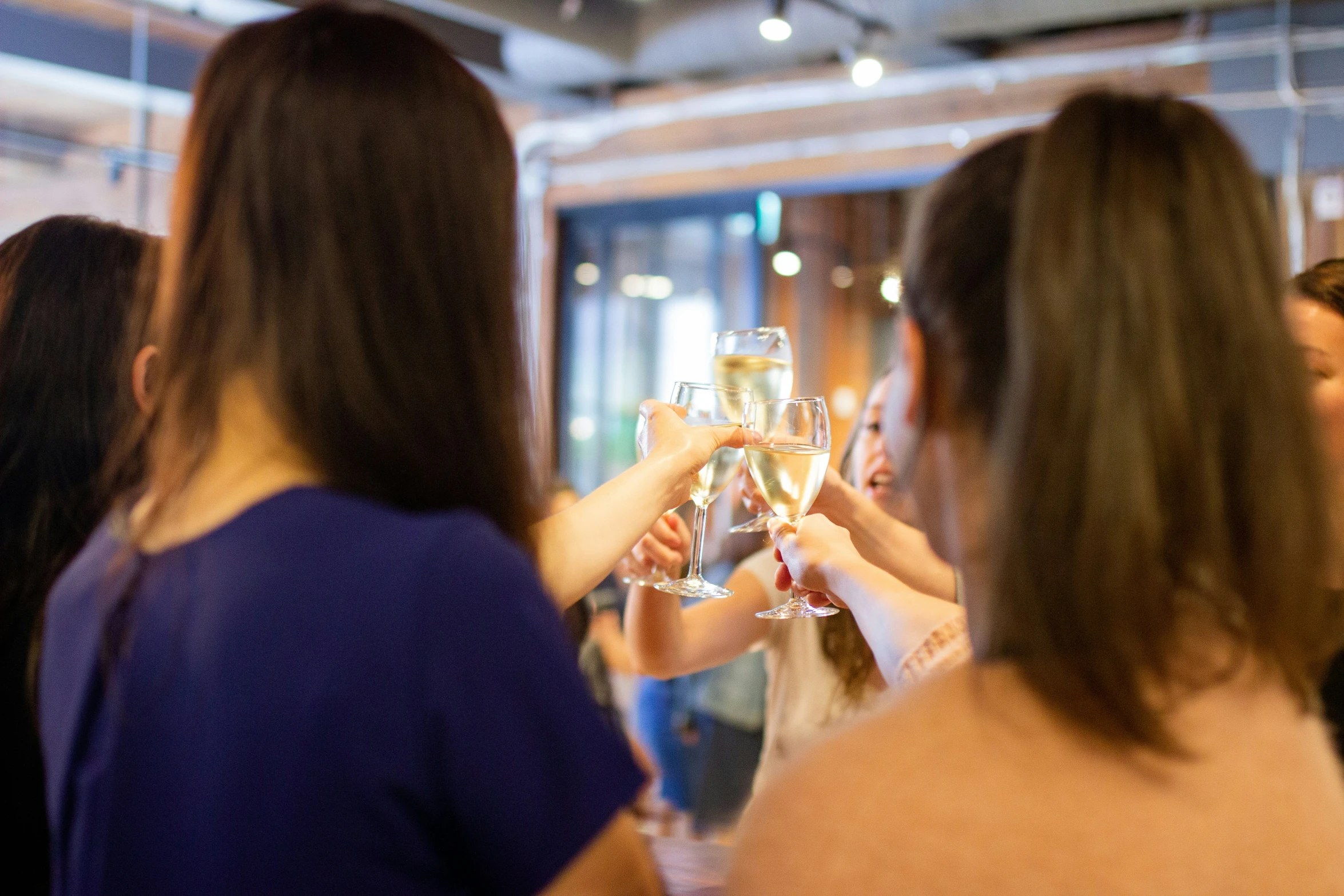 a group of people toasting and holding up wine glasses