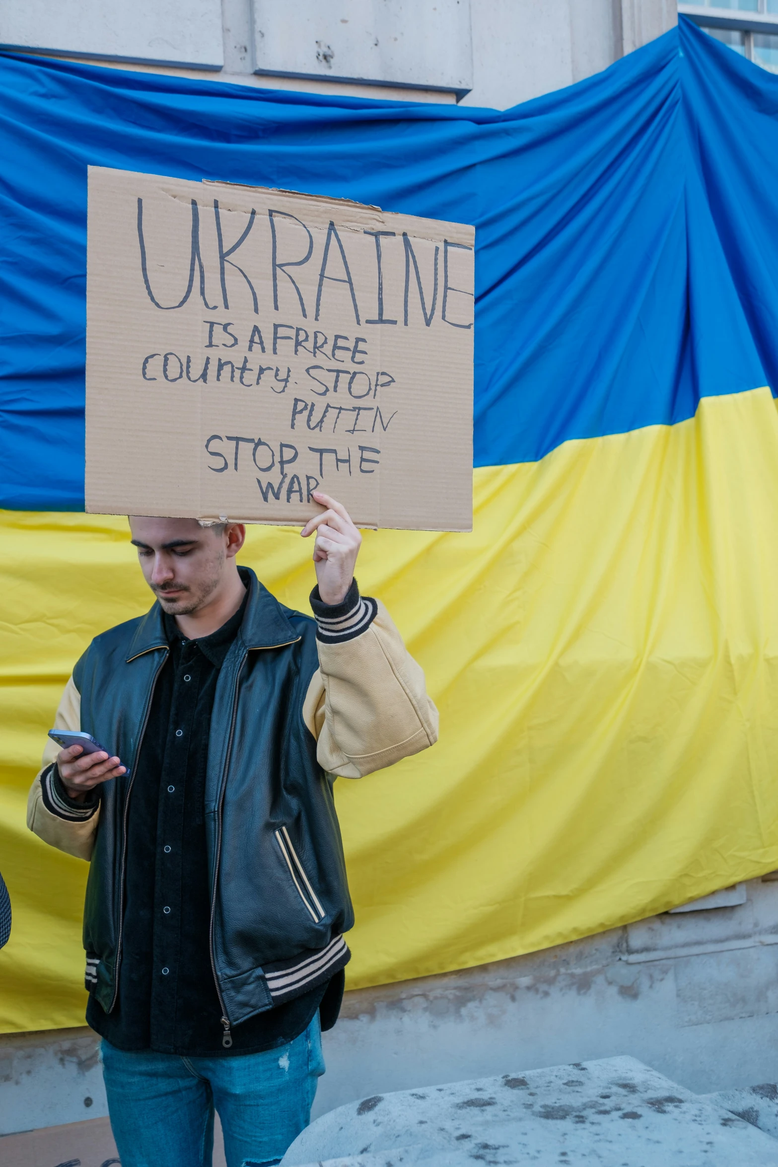 man with a cardboard sign holding up a phone