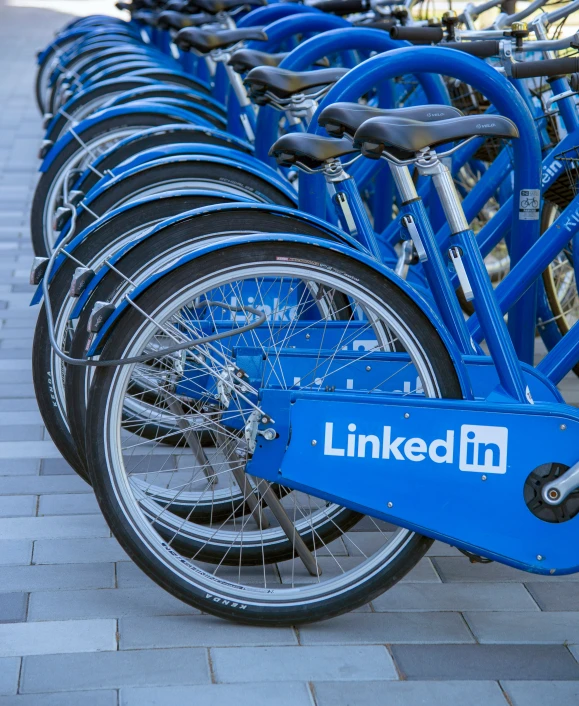 row of bikes parked on brick walkway with linked logo