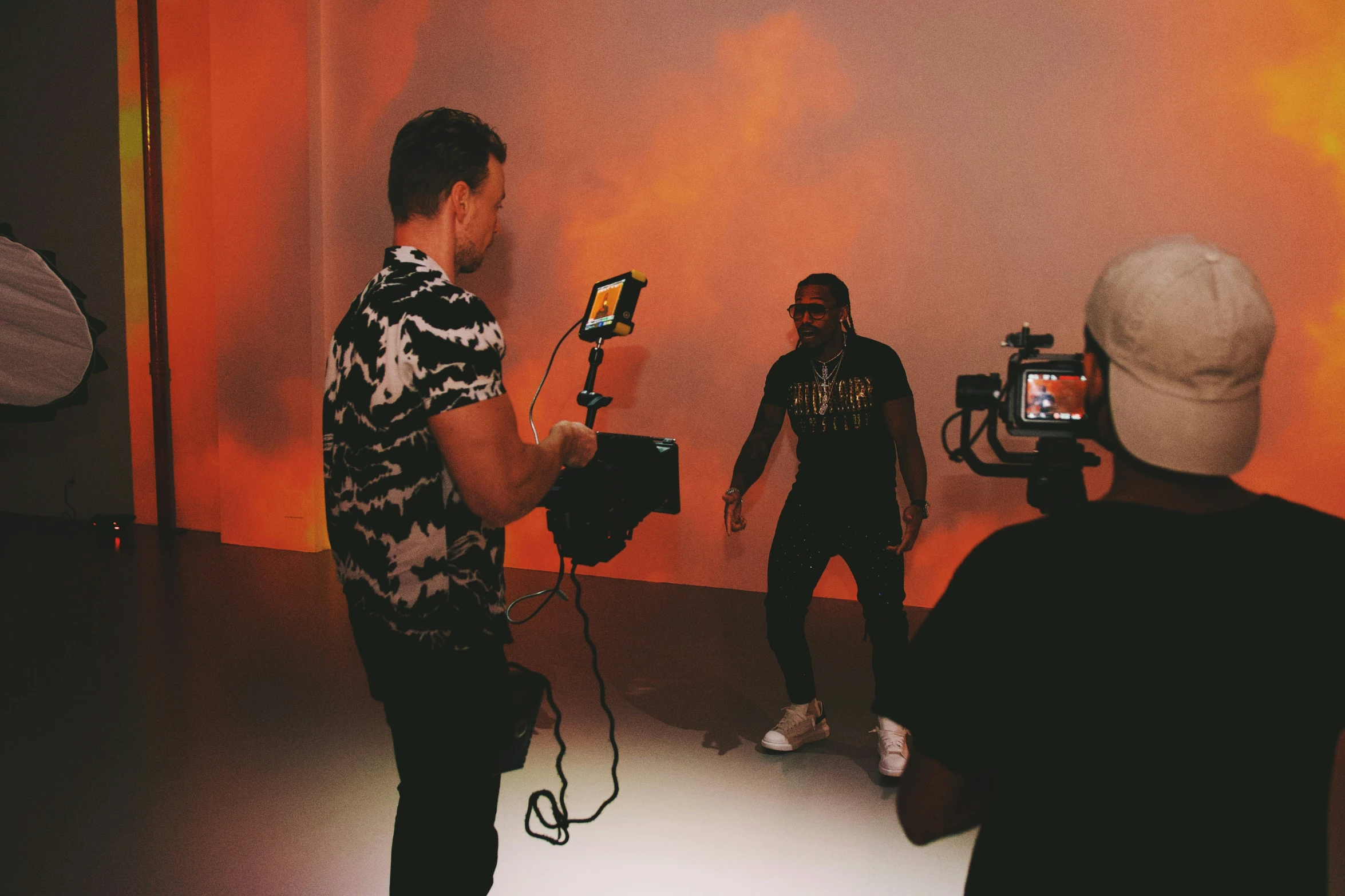 two men are filming someone in an orange room