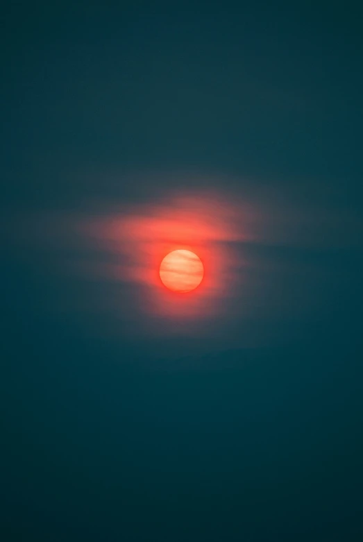 the sun setting over the ocean on a very hazy day