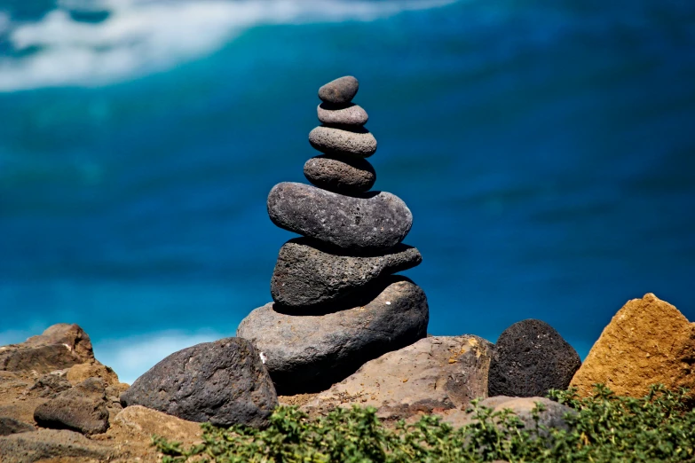 two rocks are stacked high up against the beach