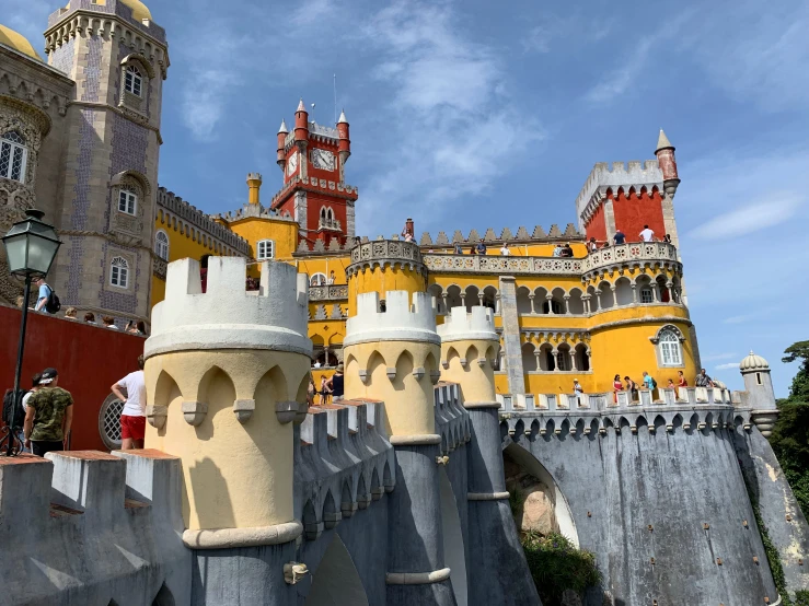 a yellow castle like building sitting next to an old brick wall