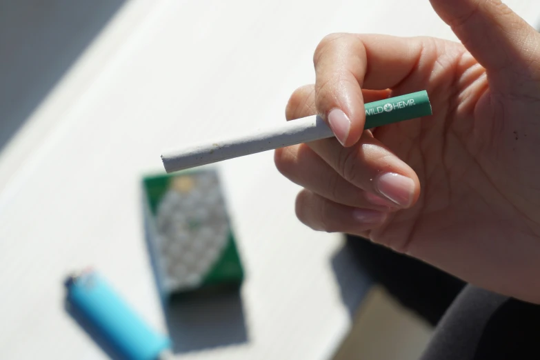 a hand holding a cigarette lighter with green stick