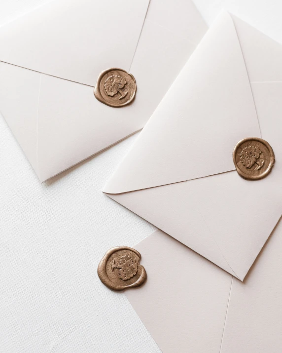 a white envelope and stamp with gold wax seals