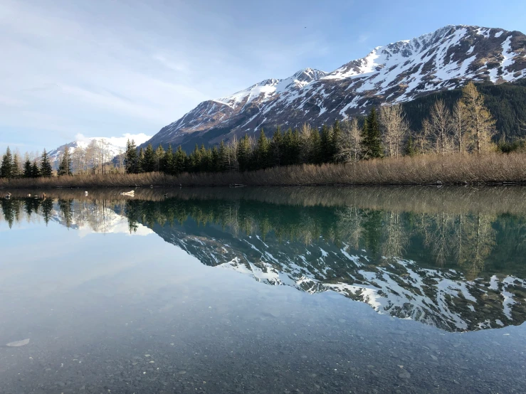 a mountain range with water and trees near by