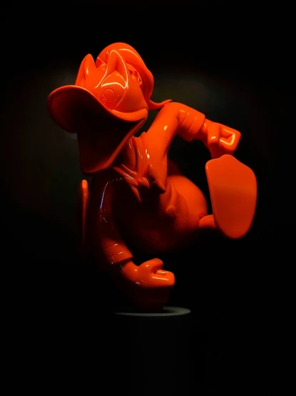 a small orange vase with a plastic man on the body