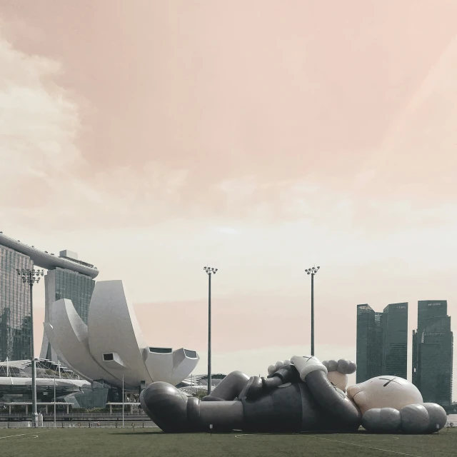 some giant sculptures are in the grass near tall buildings