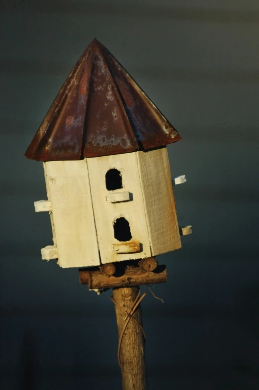 a bird house hanging off the side of a wooden pole