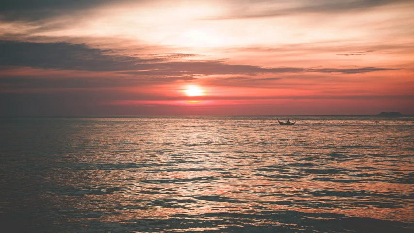 a sailboat sailing in the water at sunset