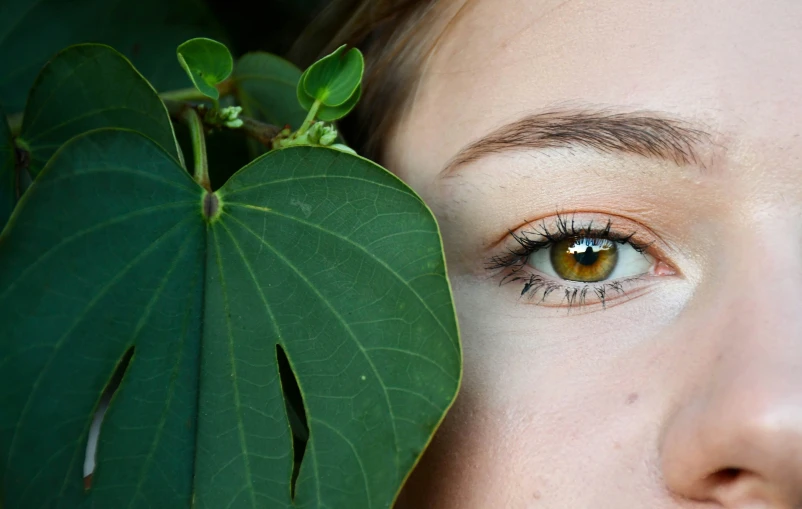 a woman with green eyes and a leaf behind her