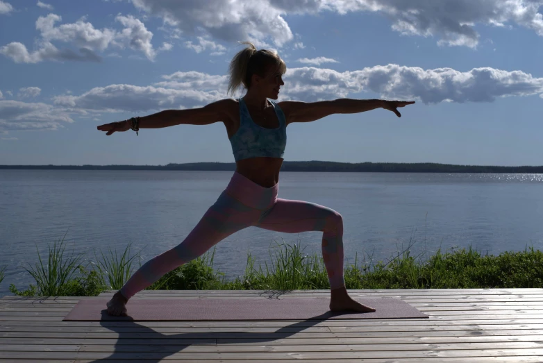 a woman practices a yoga pose on a boardwalk