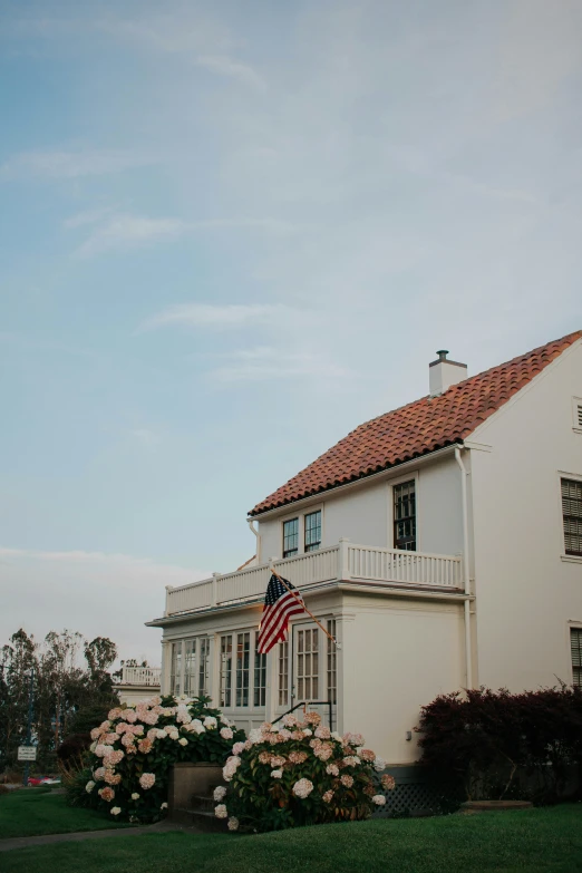 the front of a large white house with a flag flying