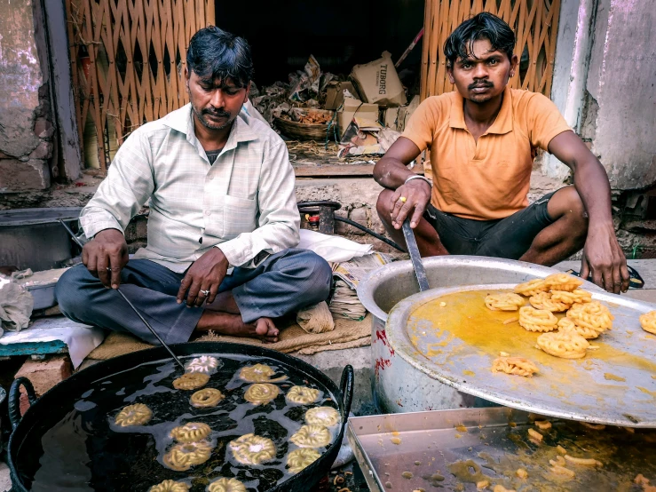 two men are sitting on the floor by some food