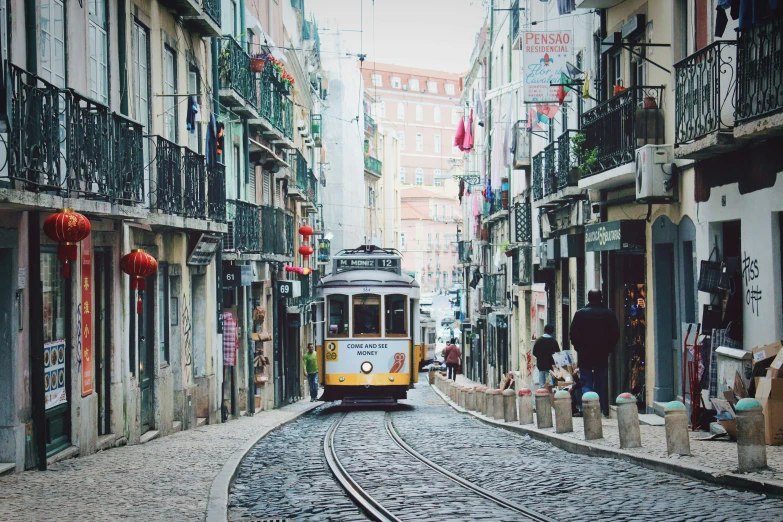 the trolley is traveling down the tracks through the narrow alleys