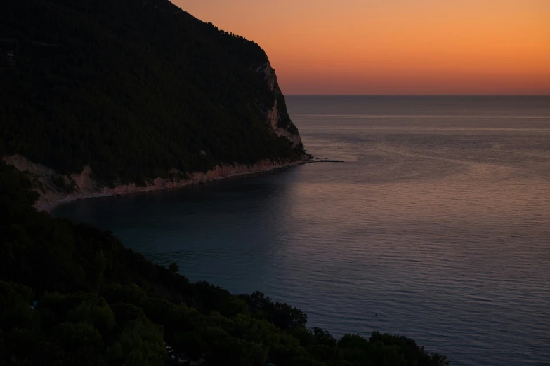 a boat glides past a large mountain in the middle of the ocean