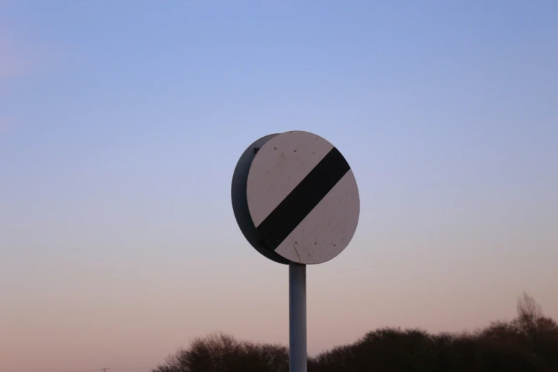 the top of a black and white street sign near the trees