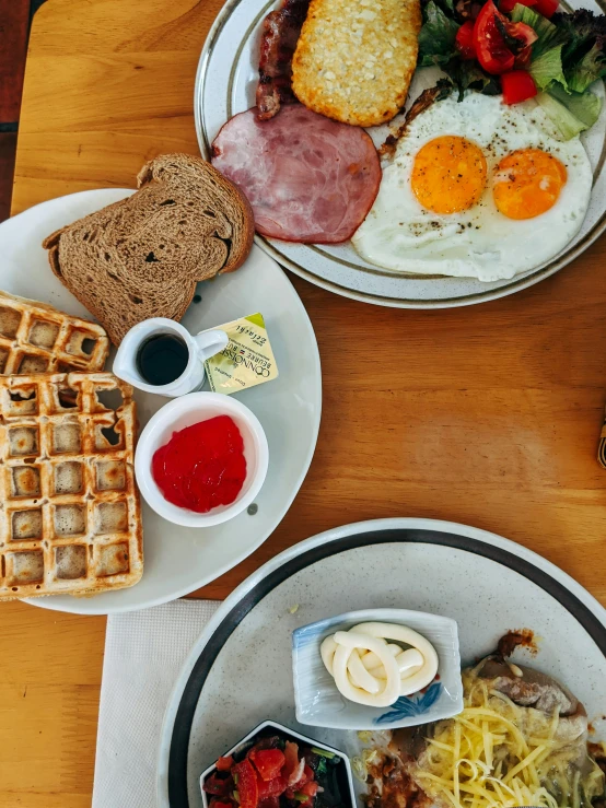 plates are full of breakfast foods that include eggs, sausages and waffles