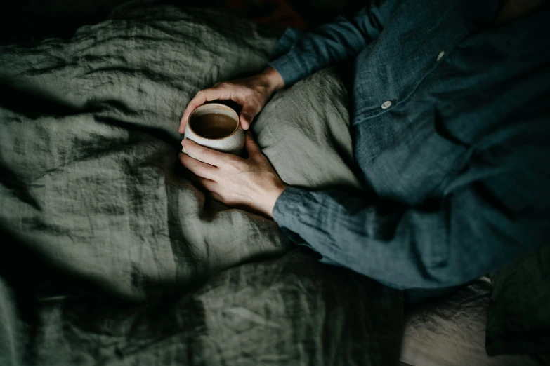 a person with a cup of coffee on a bed