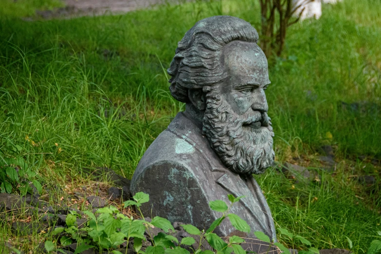 an old marble statue of a man sitting on a field