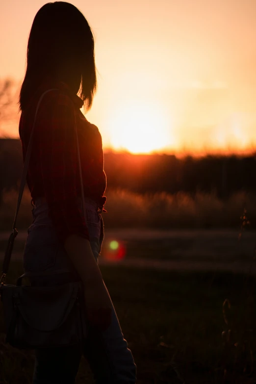 a woman walking across the grass holding a purse