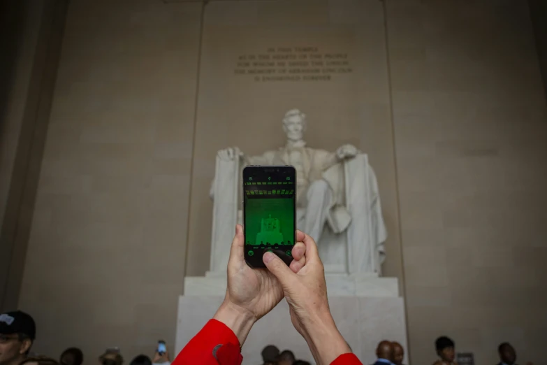 someone holding up a phone in front of a statue