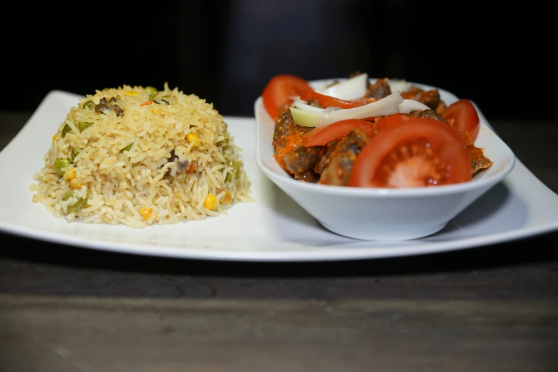 a plate with rice and veggies with tomato and other foods