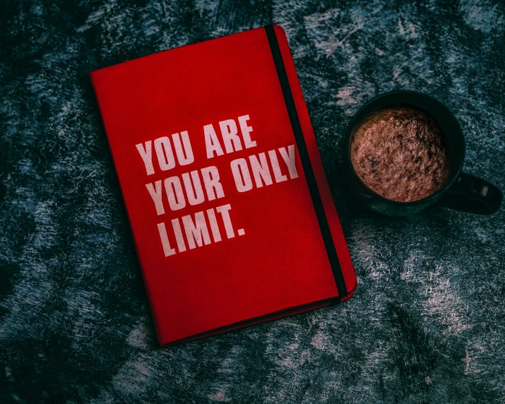 the book you are your only limit on the table next to a cup of coffee