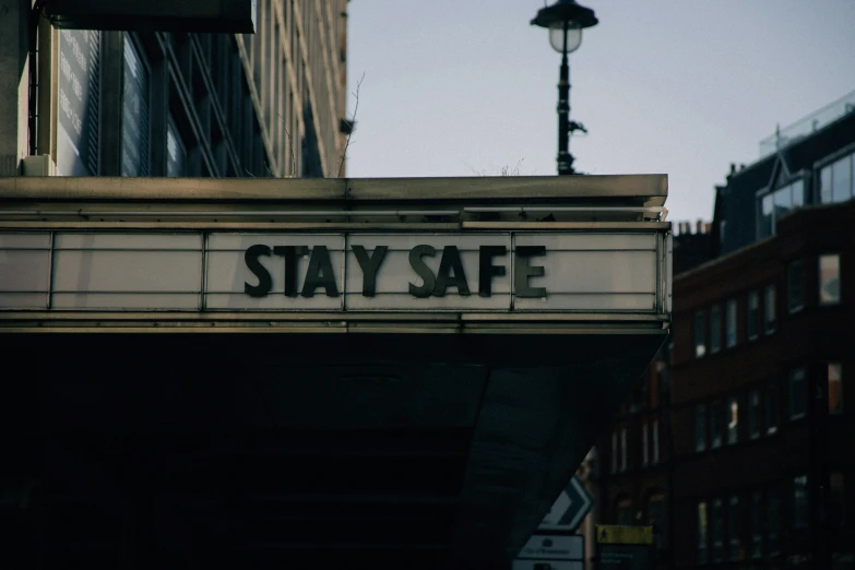 an old theater sign saying stay safe below a street light