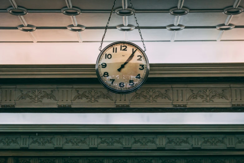 a clock hanging from a ceiling in a train station