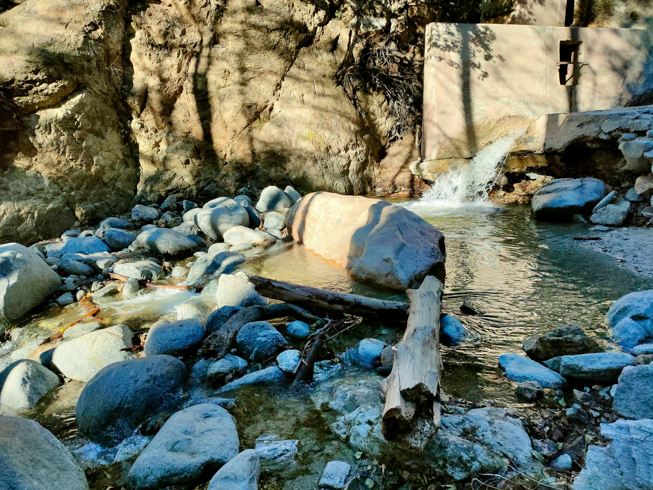 a large rock in the middle of a stream with trees surrounding it