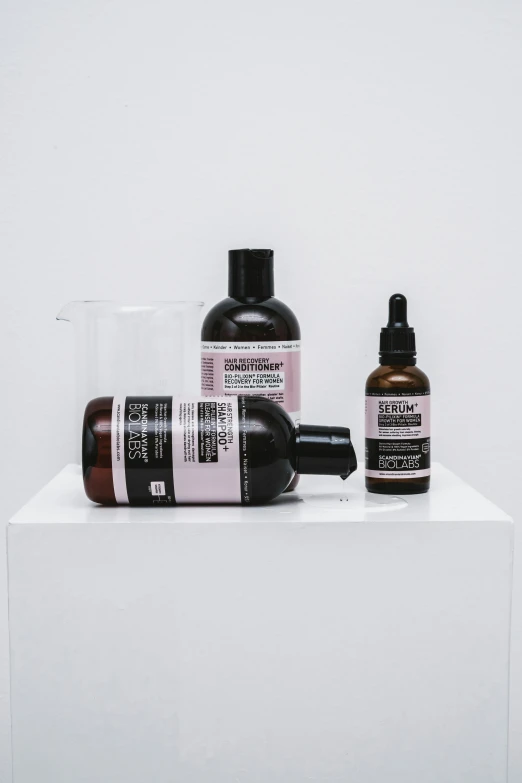 three different sized bottles and an empty container sitting on a counter